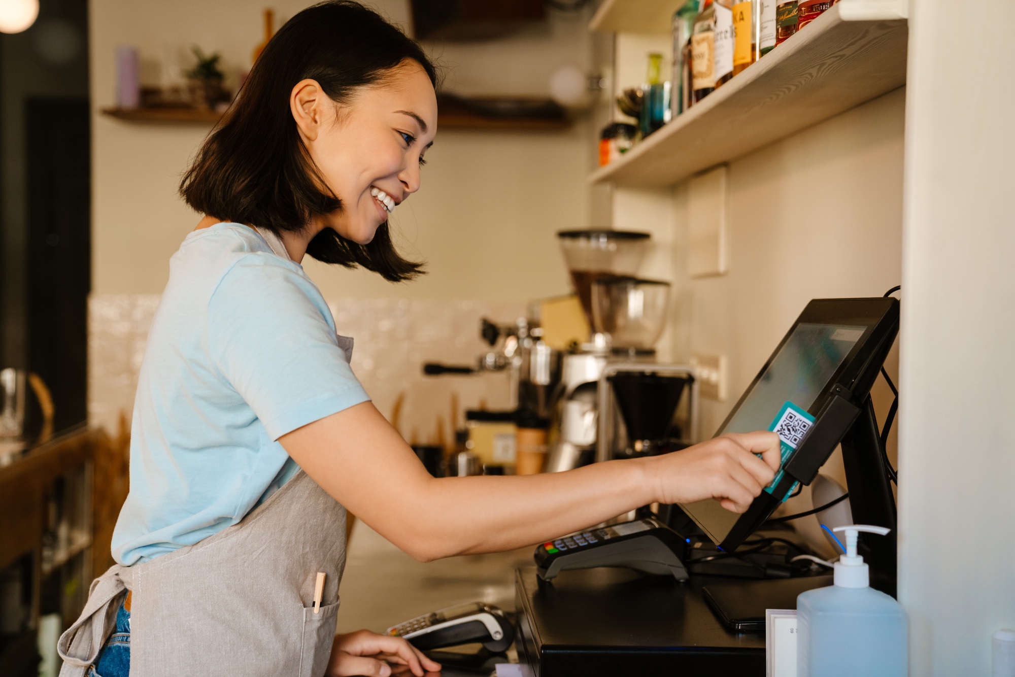 Asian barista woman smiling while working with cash register